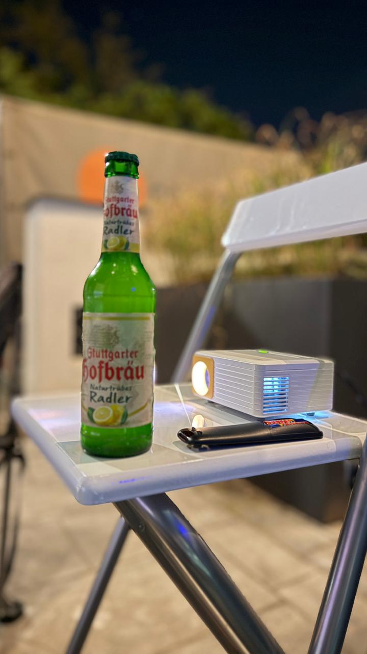 A Stuttgarter Hofbräu Naturtrübes Radler bottle beside a projector during an outdoor World Cup screening