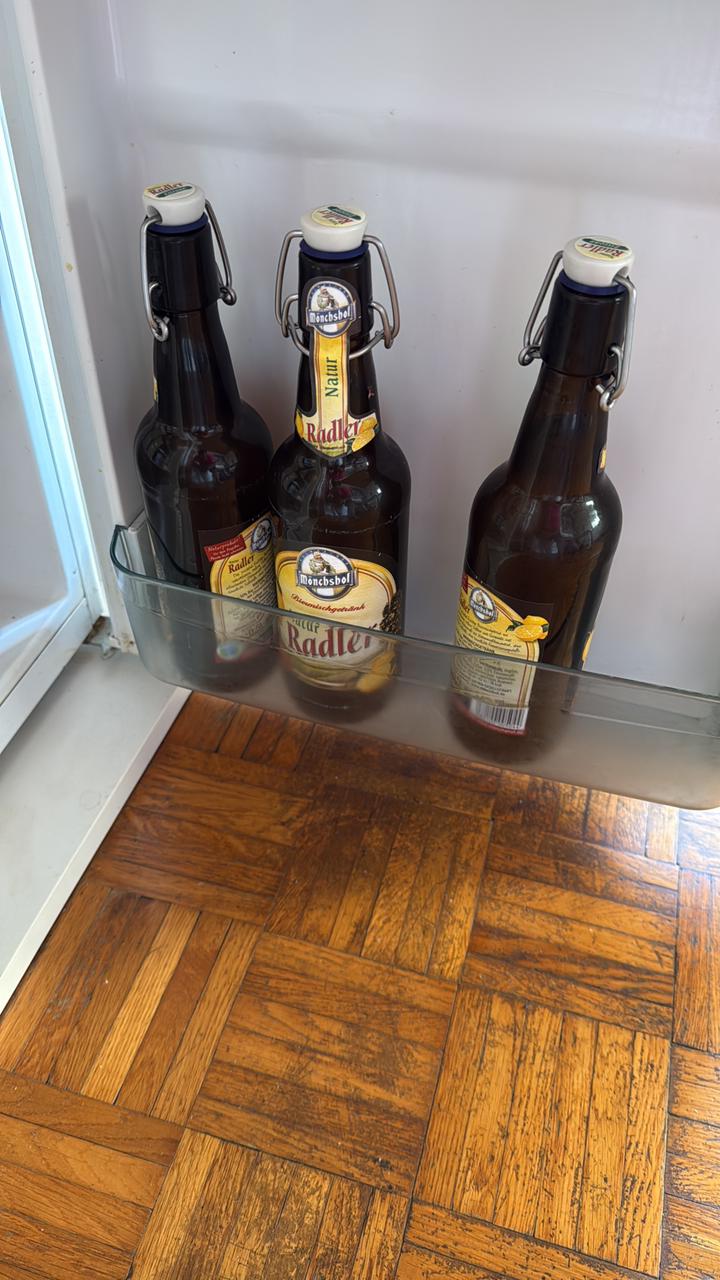 Three swing-top bottles of Mönchshof Natur Radler standing in a refrigerator door